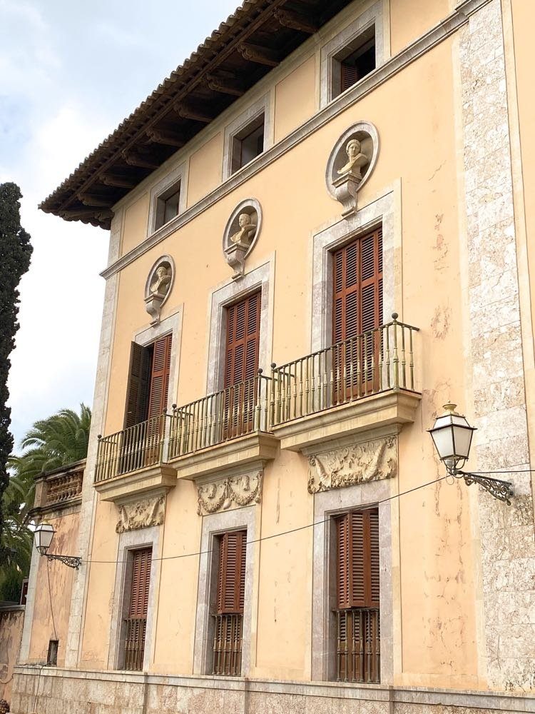 Façade of a historic palacio in a Mallorcan town with sculpted busts, carved stonework and wooden shutters